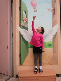 Optical illusion of girl with angel wings painted on wall