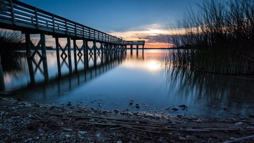 View of footbridge over river at sunset