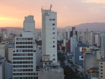 Modern buildings in city against sky during sunset