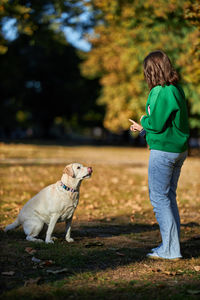 Young woman and her obedient big dog in autumn park