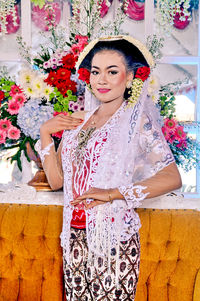 Portrait of smiling woman standing against wall