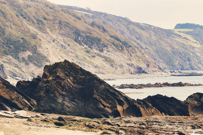 Scenic view of rocky mountains by sea against sky