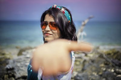 Portrait of man wearing sunglasses at beach against sky