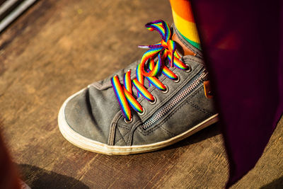 High angle view of shoe with rainbow colored laces on floor