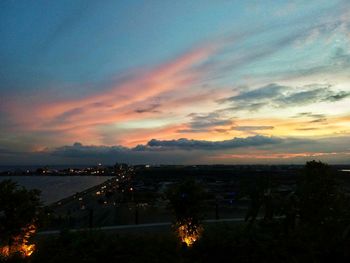 Scenic view of illuminated city against sky at sunset