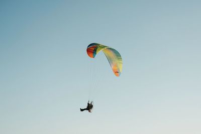 Low angle view of person paragliding against clear sky