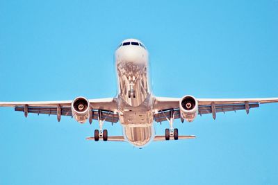 Low angle view of airplane against clear blue sky