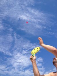 Low angle view of shirtless man playing matkot against blue sky
