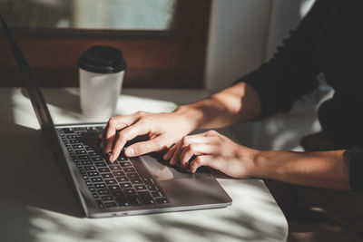 Midsection of woman using laptop at table