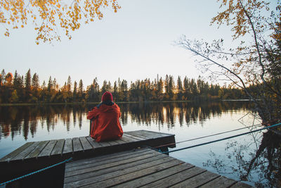 Rear view of man walking on pier over lake against sky