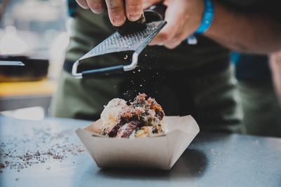 Midsection of chef garnishing food on table