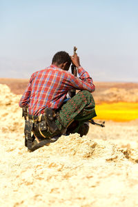 Rear view of man using mobile phone against sky