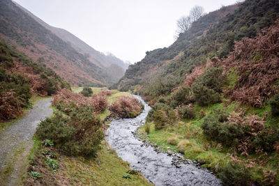 Scenic view of mountain by stream against sky