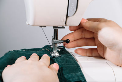 Cropped hands of woman using sewing machine