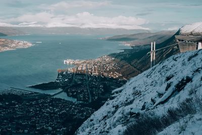 High angle view of sea by snowcapped mountains against sky