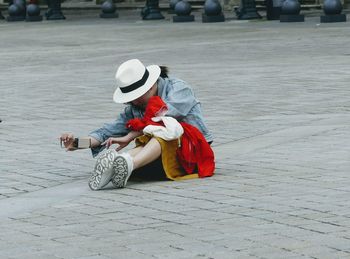 High angle view of woman sitting on footpath