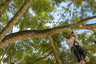 Low angle view of girl on zip line against tree