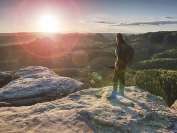 Photographer on mountain cliff above valley hold tripod. hiker take picture with camera in hands