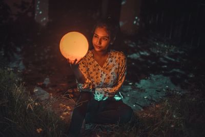 Young woman sitting on field at night