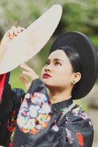 Close-up of young woman wearing traditional clothing holding hand fan