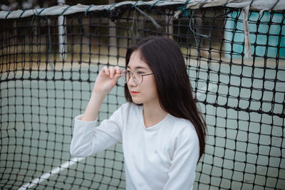 Young woman against tennis net at court