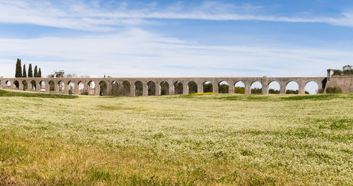 Arch bridge on field against sky