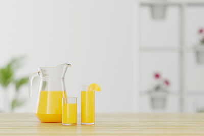 Orange juice in glasses and jar on table at home