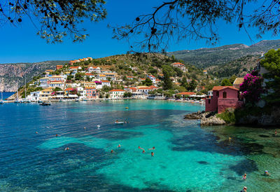 Scenic view of sea by buildings against clear blue sky