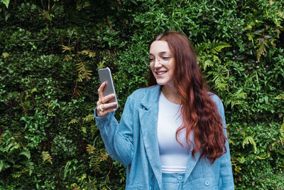 Attractive business woman smiling while writing a message in a mobile phone, empty space for text