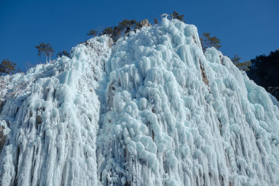 Low angle view of snow against clear blue sky