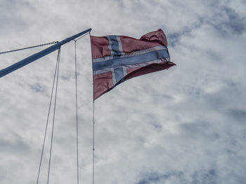 Low angle view of flag against cloudy sky