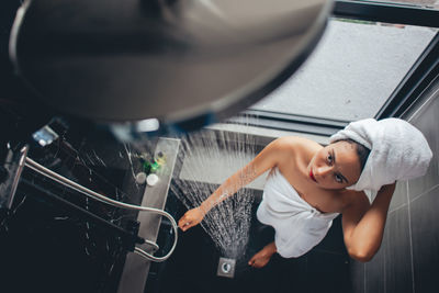 Woman looking at shower while standing in bathroom