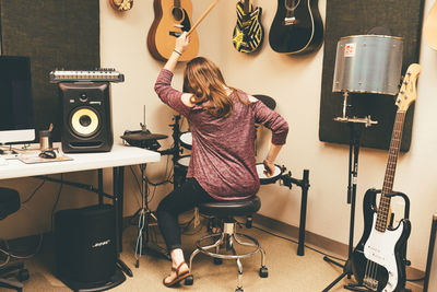 Full length of woman sitting on guitar