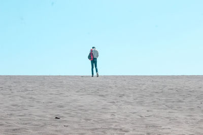 Full length of man standing on beach against clear sky