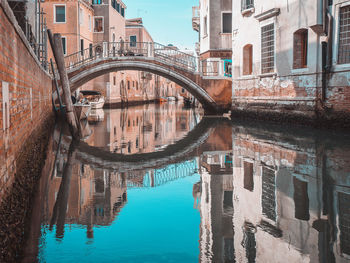 Arch bridge over canal amidst buildings in city