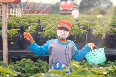 Portrait of smiling young woman standing by plants