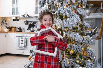 Portrait of cute girl playing with christmas tree