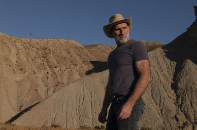 Adult man in cowboy hat on desert against mountain. almeria, spain