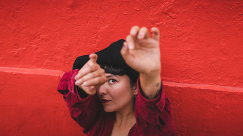 Dark-haired female model in vintage clothing and make-up against a colorful wall.