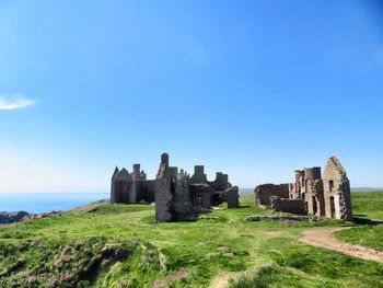 Old ruin building on field against clear blue sky