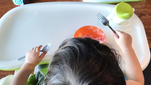 High angle view of baby girl having food at table