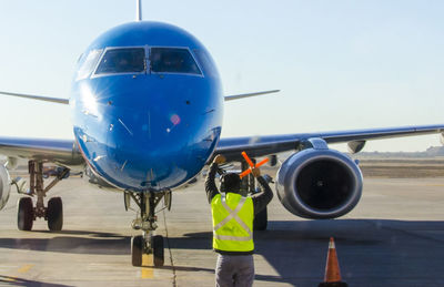 Man standing at airport runway against sky