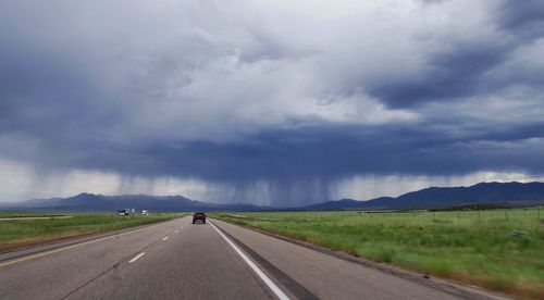 Road amidst field against sky