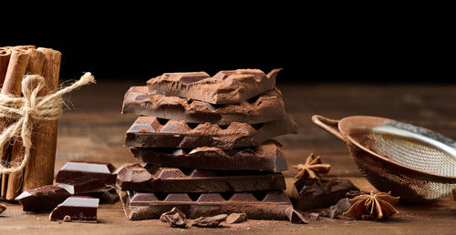 Broken pieces of dark chocolate, cinnamon sticks and star anise on a brown wooden table