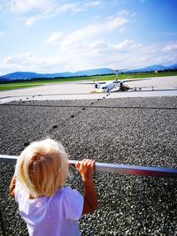 Rear view of boy on motorcycle against sky