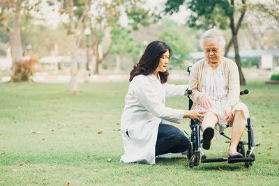 Nurse examining senior woman sitting on wheelchair at park