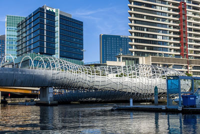 Modern buildings by river against sky in city