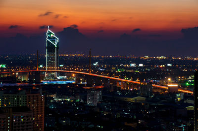 Illuminated buildings in city at sunset