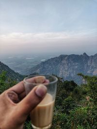 Midsection of man holding ice cream against mountains