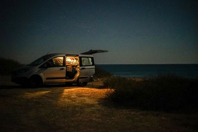 Car on road by sea against clear sky at night